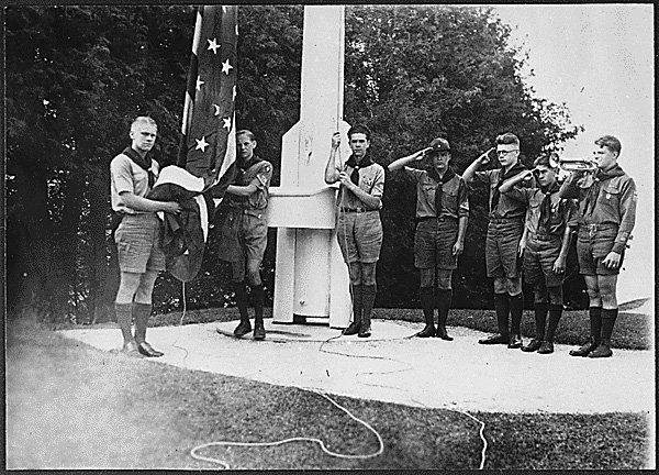 Gerald R. Ford (left) holds the flag as he and his fellow members of the Eagle Scout Guard of Honor prepare to raise the colors over Fort Mackinac at Mackinac Island State Park, Mich. The troop served as guides during the summer months of 1929.