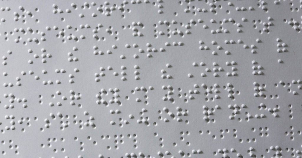 A close-up of Braille text inside the Wolf Handbook for Cub Scouts.