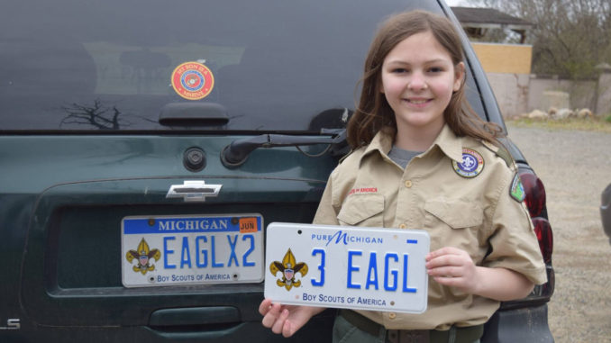 Michaela holds a license plate saying "3 Eagle"