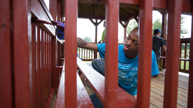 Scout painting a fence