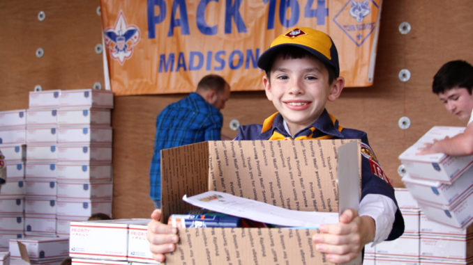 Cub Scout holding care package.