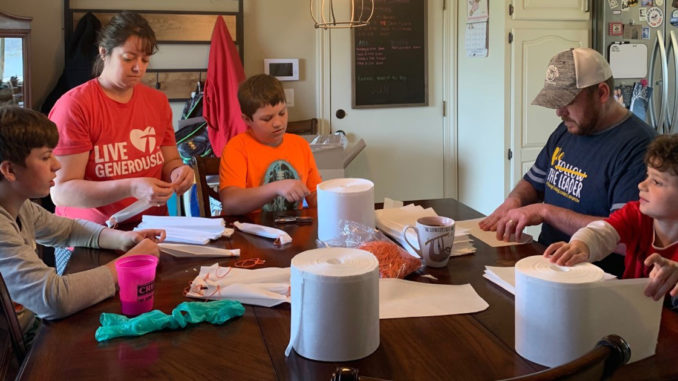 A family from Troop 599 works together to assemble face coverings