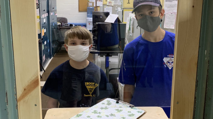 Lucas Davis (right) stands behind the plexiglass shield he constructed for his Eagle project. Among Lucas’ project helpers: his cousin Nathan Davis (left), part of his pandemic cohort — individuals in his family who are only seeing each other.
