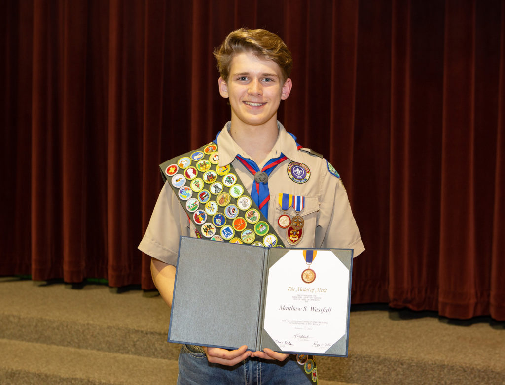 A Scout holds his Medal of Merit certificate