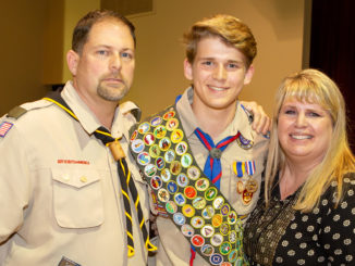 A Scout poses with his parents.