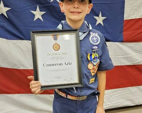 Cub Scout Cameron Aziz holds his Medal of Merit plaque