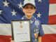 Cub Scout Cameron Aziz holds his Medal of Merit plaque