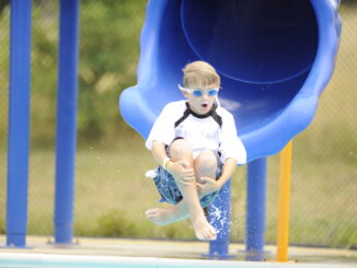 A Scout enters the pool via a waterslide