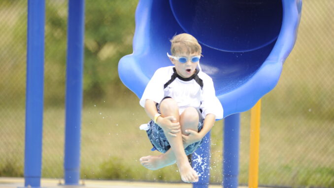 A Scout enters the pool via a waterslide