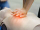 A photo of hands performing chest compressions on a practice mannequin