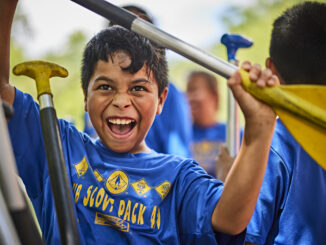 Cub Scout holding a paddle for a canoe or kayak; very excited; excitement