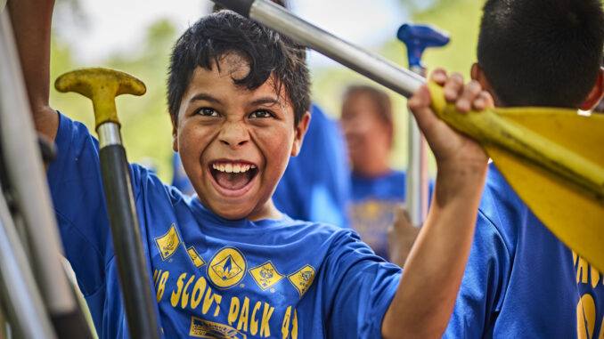 Cub Scout holding a paddle for a canoe or kayak; very excited; excitement