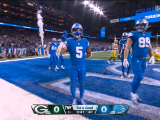 A screen capture of David Montgomery flashing the Scout salute after scoring a touchdown