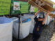 A Cub Scout drops off a piece of cardboard into a recycling bin operated by the Cherokee Area Council