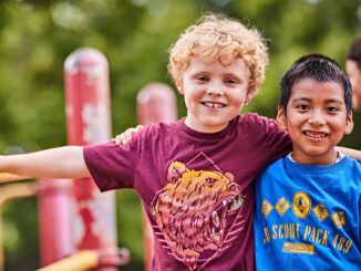 Adventure On 2023 Social Media Image - #AdventureOn - Two cub scouts with arms around each other at the playground; jungle gym; friends; pals