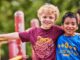 Adventure On 2023 Social Media Image - #AdventureOn - Two cub scouts with arms around each other at the playground; jungle gym; friends; pals
