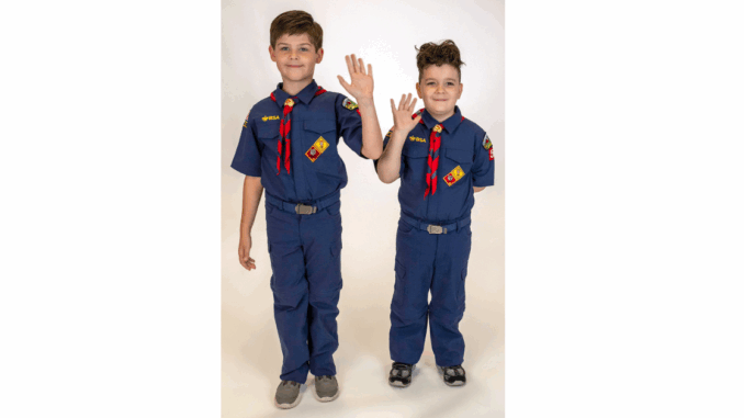 A photo of two Cub Scouts waiving while wearing their uniforms