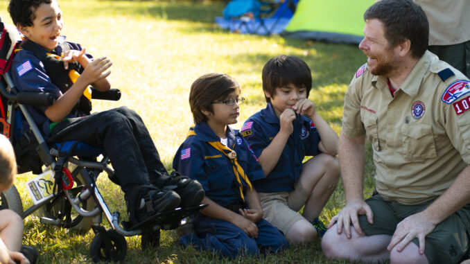 Wolf Cub Scouts at a pack meeting outside with a scout in a wheelchair