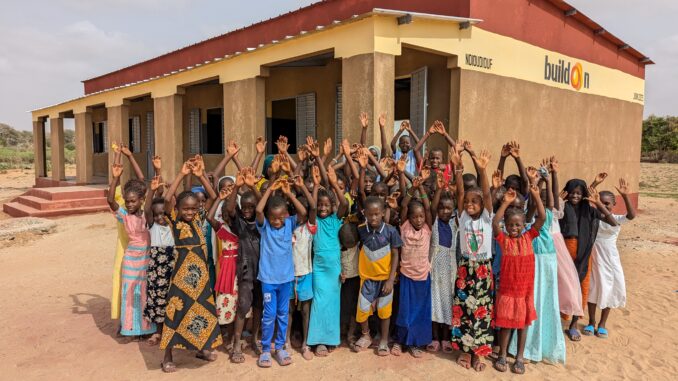 A group of children stand in front of the finished school in Ndioudiouf, Senegal